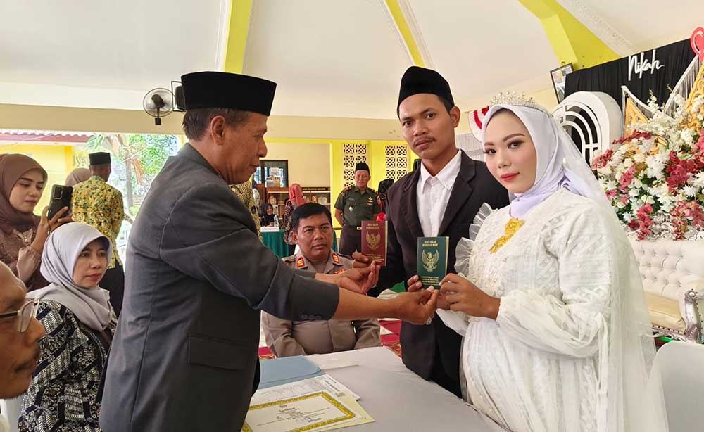 Salah satu mempelai menunjukkan buku nikah usai melaksanakan akad.