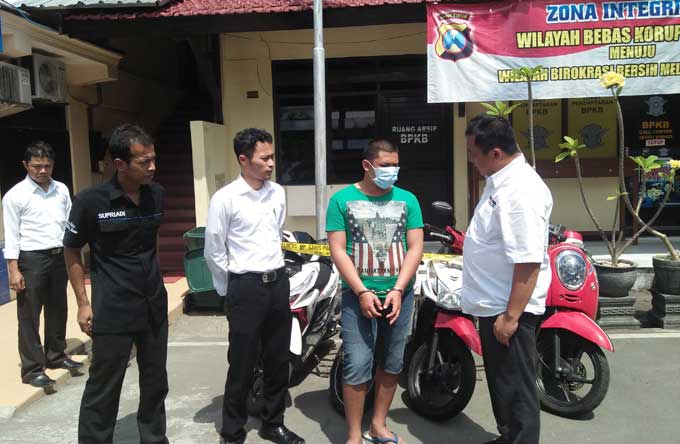 Pelaku (kaos hijau) bersama sejumlah barang bukti saat diamankan di Mapolresta Blitar. foto: AKINA/ BANGSAONLINE