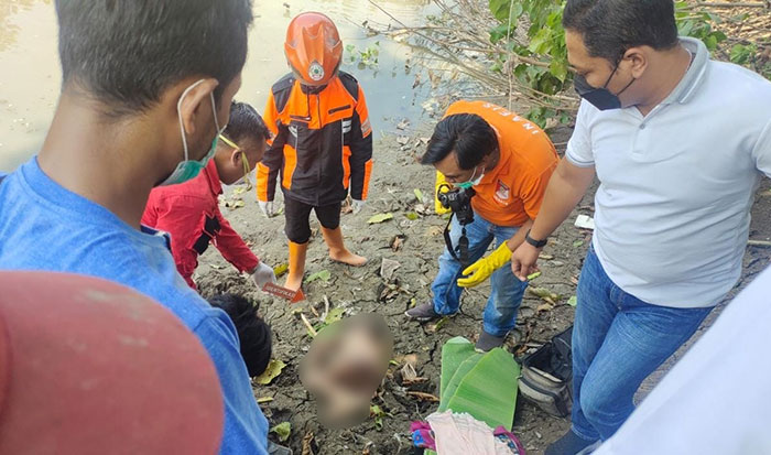 Petugas saat mengevakuasi mayat balita yang ditemukan di bantaran sungai.