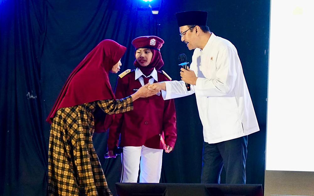 Menteri Sosial Saifullah Yusuf menyalami salah satu wali murid Sekolah Rakyat yang anaknya tampil di panggung saat acara dialog Kesejahteraan Sosial dan Sekolah Rakyat di Gedung Kesenian Darmoyudo, Kota Pasuruan.