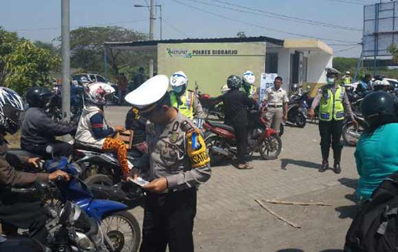 PERIKSA: Kasatlantas Polres Sidoarjo, AKP Bayu Prasetyo turun langsung dengan memeriksa kelengkapan kendaraan dari pengendara dalam Operasi Zebra Semeru 2015 di  Exit Tol Porong. foto: catur andy erlambang/BANGSAONLINE