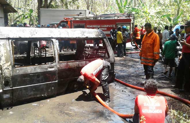 Petugas pemadam kebakaran saat memadamkan api mobil jenis L300 yang terbakar.