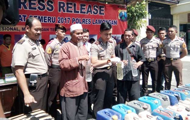 Petugas menunjukkan miras hasil razia pekat.