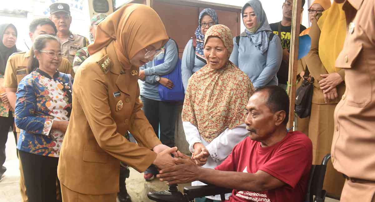 Wali Kota Kediri saat menyalami Tri Agus Winarno penerima bantuan kursi roda. Foto: Ist