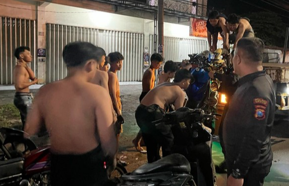 Puluhan remaja yang terjaring razia balap liar oleh Polres Gresik saat diminta mengangkut kendaraan mereka ke mobil bak petugas.