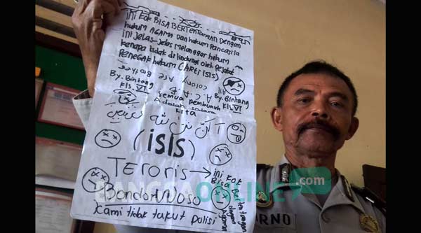 Petugas Polsek Tenggarang saat menunjukkan bukti tulisan dukungan kepada ISIS yang diduga ditulis oleh BN. foto: sugiyanto/ BANGSAONLINE