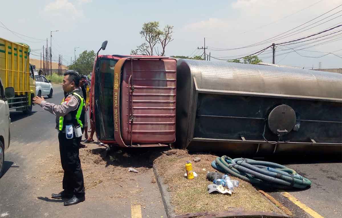 Petugas saat mengatur lalu lintas akibat truk tangki air yang terguling di Sidoarjo.