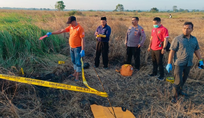 Petugas memasang garis polisi di lokasi penemuan mayat.