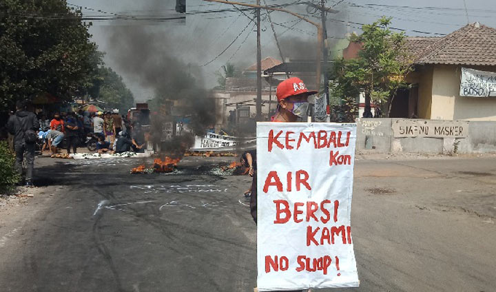 Aksi warga Desa Baujeng memprotes bau limbah dengan menutup jalan dan membakar ban.