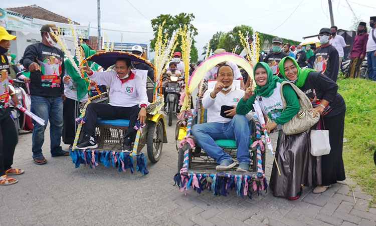Pasangan Qosim-Alif saat menyapa pendukungnya dengan naik becak. (foto: ist)