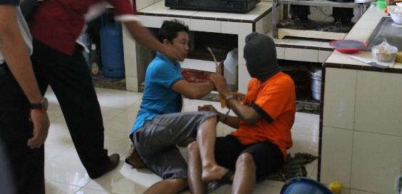 Tersangka saat memperagakan pembunuhan terhadap korban. (Try Susanto/BangsaOnline.com)
