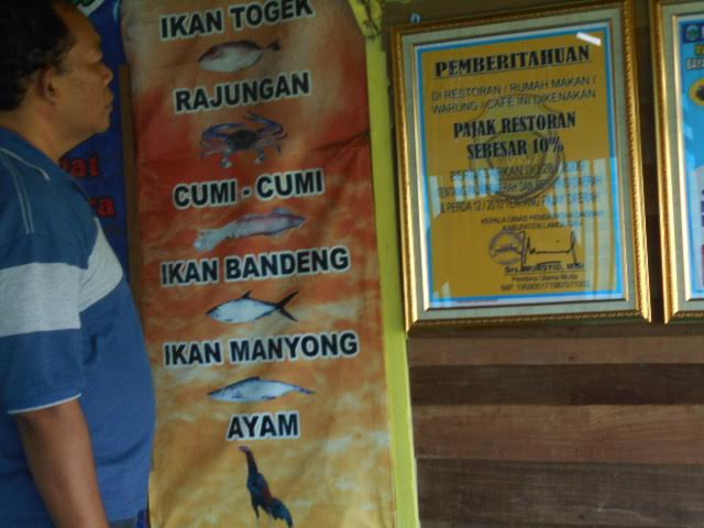 Seorang pengunjung sedang melihat pemberitahuan pajak resto.