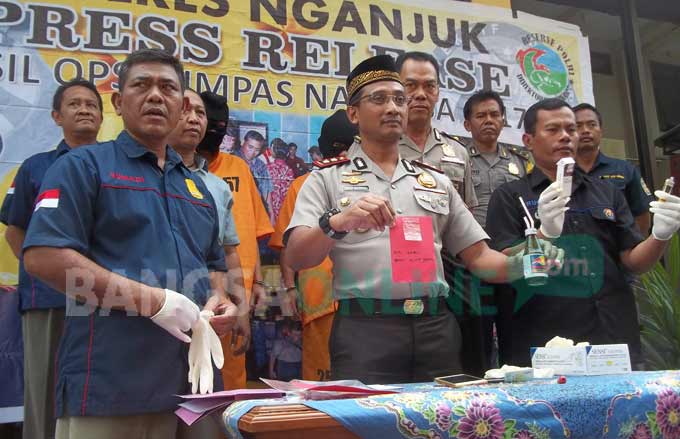 Kapolres Nganjuk AKBP Joko Sadono, saat menunjukan tersangka beserta barang bukti berupa satu poket sisa sabu dan alat hisap. foto: BAMBANG DJ/ BANGSAONLINE