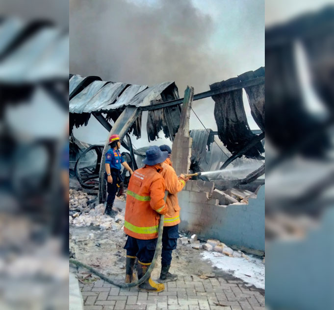 Petugas Damkar Pemkab Gresik melakukan pemadaman gudang milik PT Gunung Agung Sentosa yang terbakar.