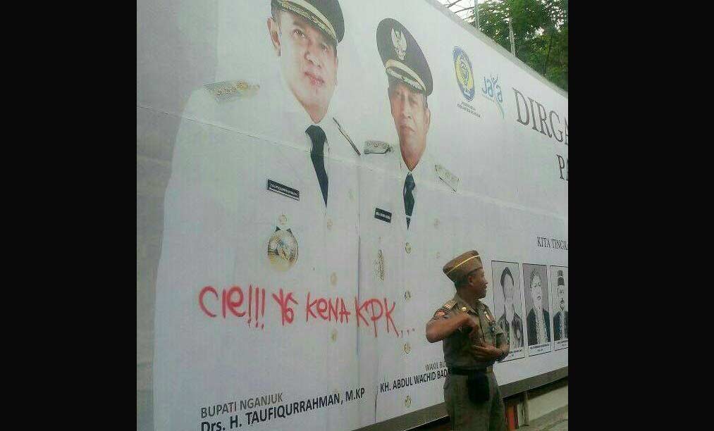 Baliho peringatan HUT Nganjuk ke-1079 yang dicoret dengan tulisan orang tak dikenal.