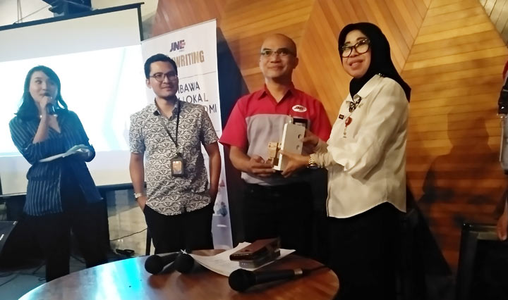Petinggi JNE Whindiarto Yudistiro memberikan cinderamata ke Plt. Kepala Dinas Koperasi dan Usaha Mikro Tri Widyani P usai acara diskusi ekonomi di Resto Dapur 63 Jalan Borobudur Lowokwaru Malang. foto: IWAN IRAWAN/ BANGSAONLINE