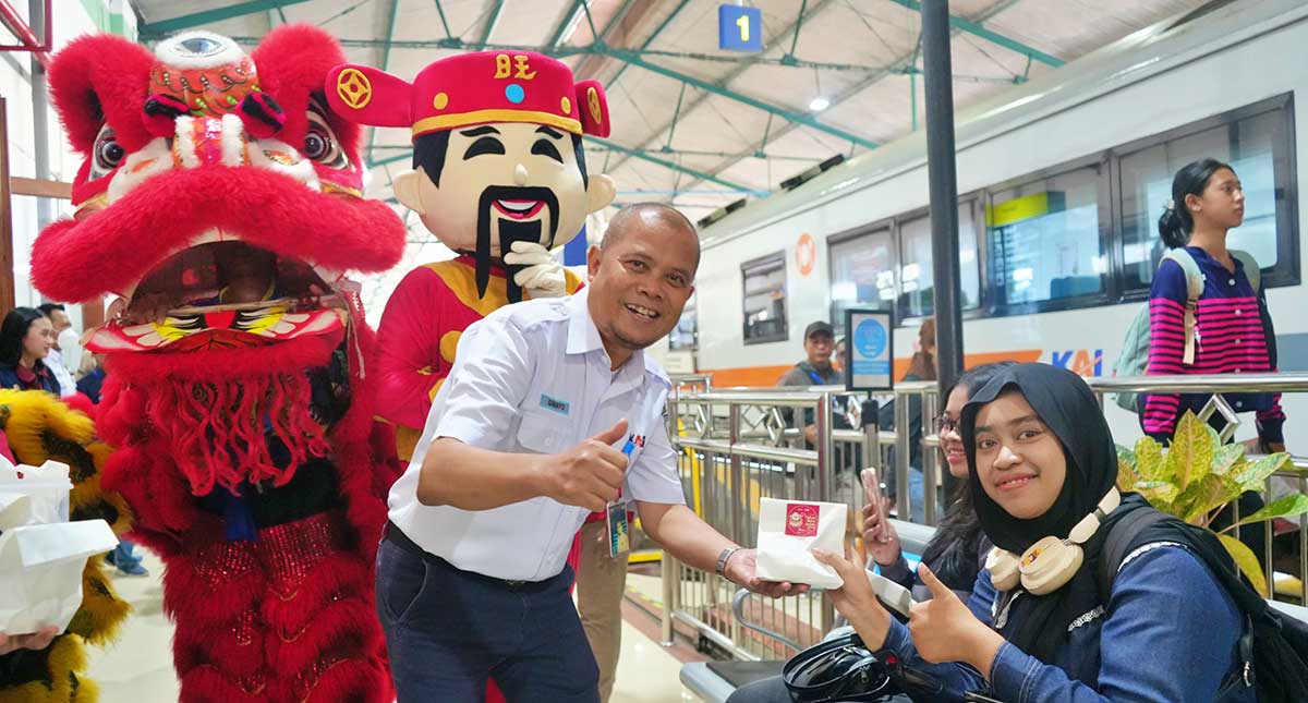 Didampingi pemain barongsai, petugas dari KAI Daop 7 Madiun saat membagikan souvenr kepada pelanggan.