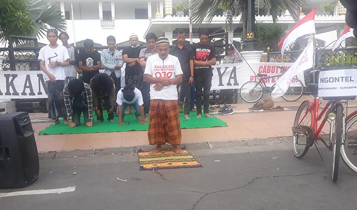 Pengunjuk rasa melaksanakan salat berjamaah di depan gerbang kantor Gubernur Jawa Timur. foto: DIDI ROSADI/ BANGSAONLINE