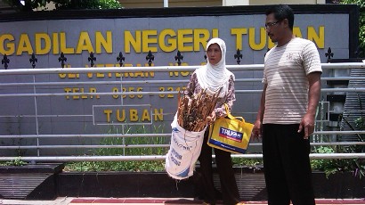 TEBON. Yuliati saat membawa sekarung tebon jagung ketika hendak diserahkan ke majlis hakim di Pengadilan Negeri Tuban. foto : suwandi/BangsaOnline.com