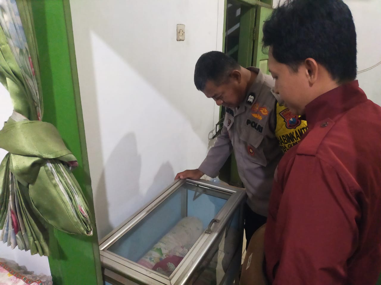 Dua anggota Polsek Beji saat melihat kondisi bayi yang ditemukan warga