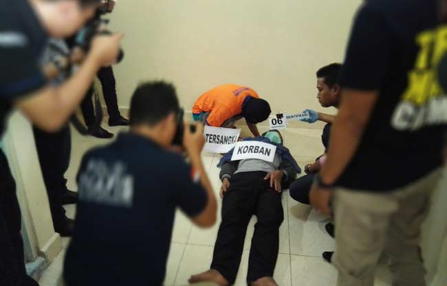 Pelaku saat memeragakan salah satu adegan cara membunuh korban. foto: SYUHUD/ BANGSAONLINE
