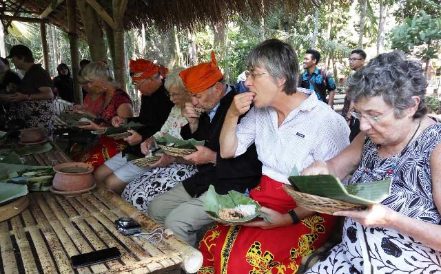 Para turis Amerika ini menkmati makan cara tradisional - tanpa sendok, di desa Kemiren Banyuwangi.