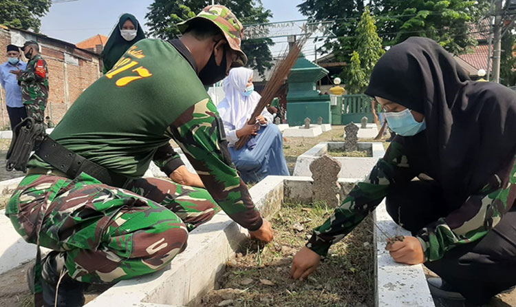 Anggota Kodim 0817/Gresik bersama para pelajar saat kerja bakti membersihkan makam pahlawan. (foto: ist)
