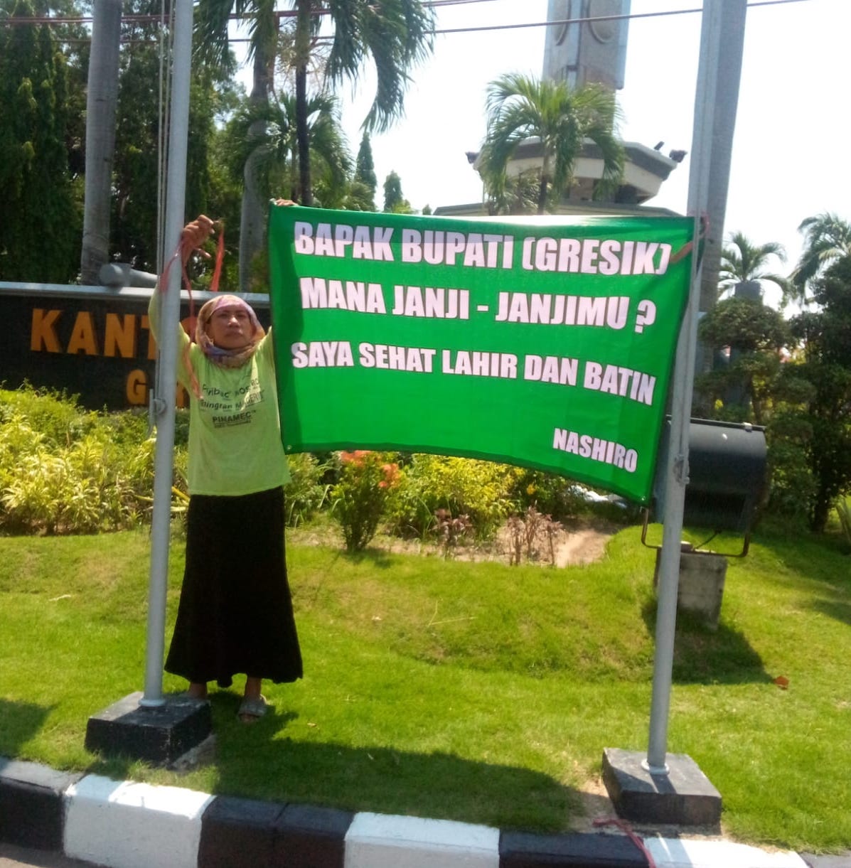 Nashiro memasang spanduk berisi tagih janji di depan Kantor Pemkab Gresik (foto: ist)