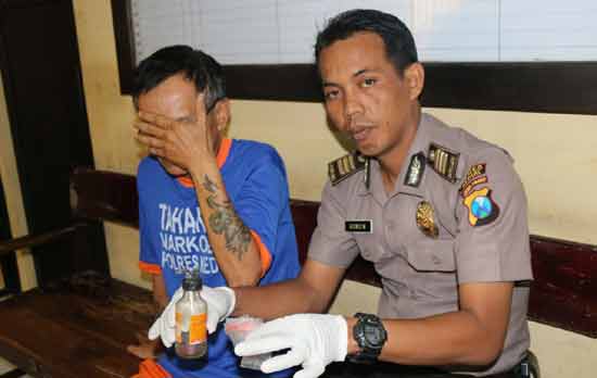 Pelaku saat diamankan bersama barang bukti oleh Polisi.