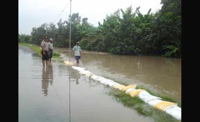 Warga gotong royong memasang sandbag untuk mencegah luberan air meluas.