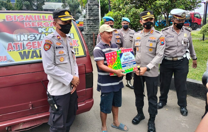 Kapolres Pasuruan AKBP Bayu Pratama Gubunagi didampingi Kapolsek Pandaan Kompol Marwan saat memberikan bingkisan sembako kepada salah satu sopir. foto: MOCH ANDY FACRUDIN/BANGSAONLINE