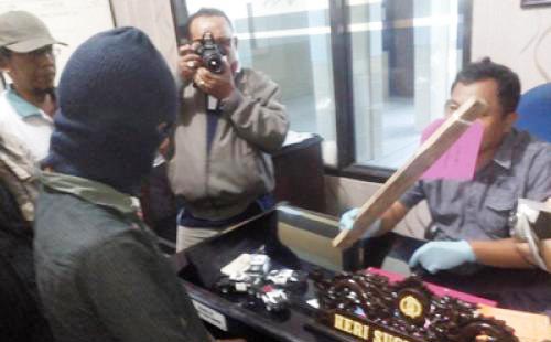 Mursalim saat diamankan beserta barang bukti sebuah balok yang digunakannya menggebuki Mulyono. (foto: beritajatim)