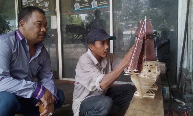 Mohamad Khoiri sedang mengerjakan miniatur perahu dari bahan dasar tusuk es krim. foto: soewandito/ BANGSAONLINE