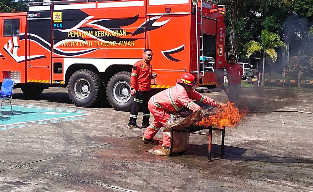 Mariksa, salah satu guru pendamping, saat mencoba memadamkan api dengan memakai seragam safety.