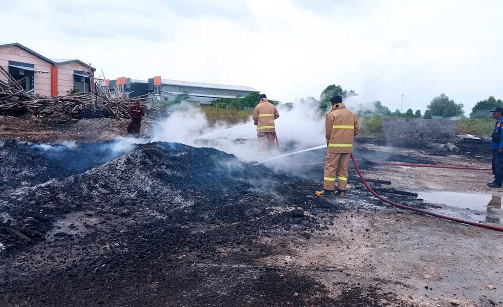 Petugas Damkar Gresik saat memadamkan kobaran api yang membakar tumpukan kayu palet. Foto: Ist.