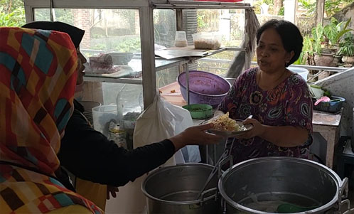 Bu Sur, saat melayani pembeli yang memesan sepiring nasi pecelnya. 