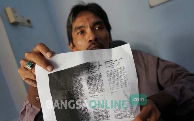Petugas Dewan Pendidikan menunjukkan lembaran fotocopy yang diduga sebagai kunci jawaban soal UN SMP. foto: rony suhartomo/ BANGSAONLINE