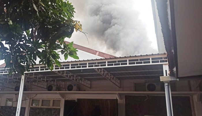 Tampak asap tebal membumbung tinggi dari atap gudang.