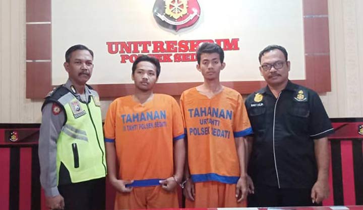 Dua dari lima pelaku penganiayaan yang berhasil ditangkap, sedang diapit petugas.