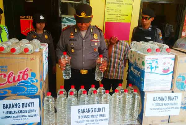 Kapolsek Rengel, AKP Musa Bachtiar ketika memamerkan hasil tangkapan ratusan liter arak. (foto: suwandi/BANGSAONLINE)