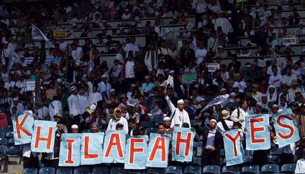 Sejumlah massa Hizbut Tahrir Indonesia (HTI) membawa banner saat mengikuti puncak acara Muktamar Khilafah 2013 di Stadion Gelora Bung Karno, Jakarta, Minggu (2/6). TEMPO/Dian Triyuli Handoko