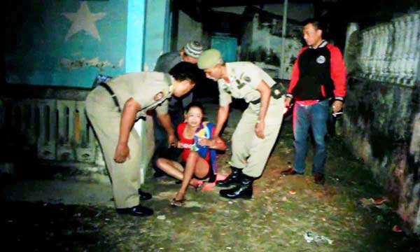 Petugas saat mengamankan PSK yang sembunyi di kebun. (foto: soewandito/BANGSAONLINE)