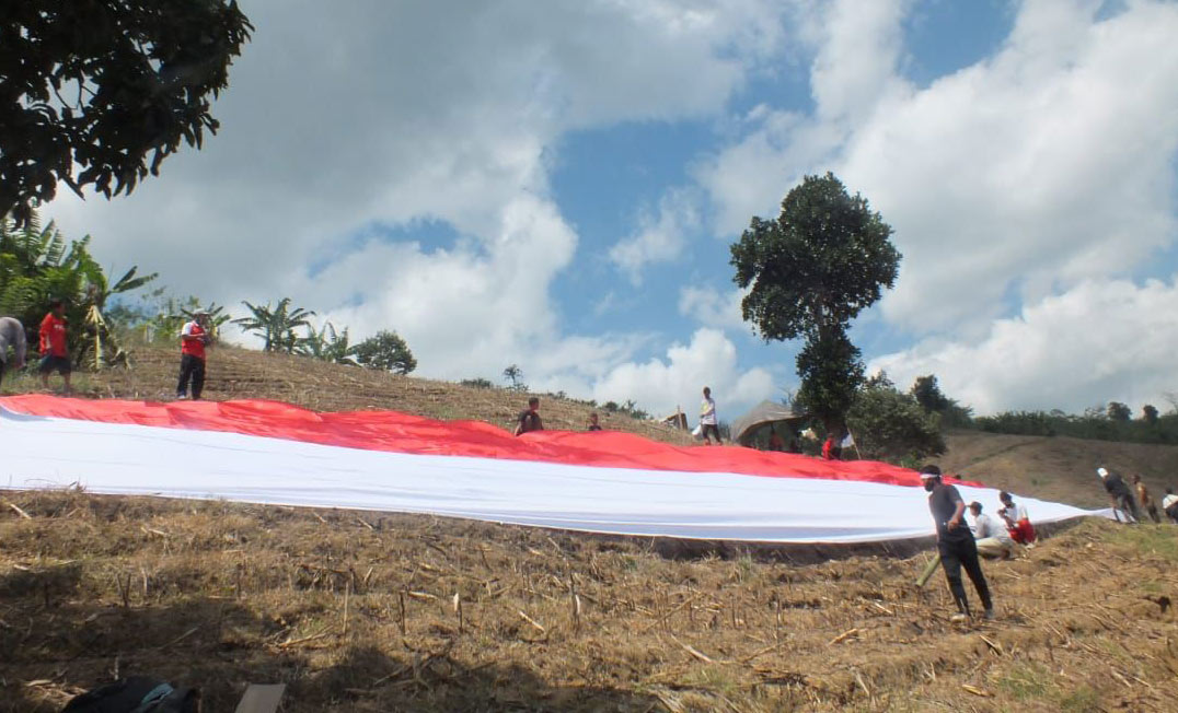 Bendera merah putih raksasa berukuran 150 x 15 meter yang dibentangkan di Bukit Tinggi Desa Lampeji Kecamatan Mumbulsari, Jember.
