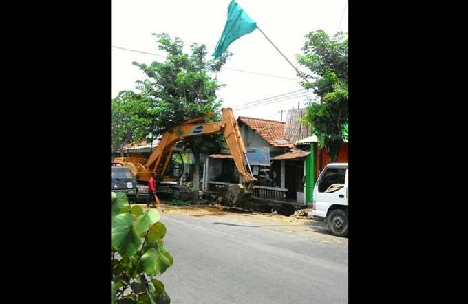 Alat berat yang digunakan untuk mengeruk gorong-gorong di salah satu jalan protokol Kota Kediri. foto: arif kurniawan/BANGSAONLINE