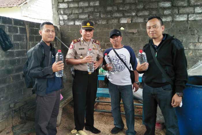 Petugas menunjukkan arak siap edar yang diproduksi di kandang kambing.