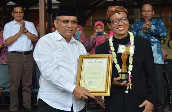 Penjabat Bupati Gresik, Akmal Boedianto menunjukkan penghargaan atas diraihnya Juara 1 Nasional oleh SMA NU 1 Gresik dalam lomba perpustakaan. foto: syuhud/BANGSAONLINE