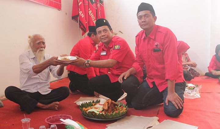 Ketua DPC PDIP Nganjuk Tatit Heru Tjhyono memberikan potongan tompeng kepada tokoh utama pendiri DPC PDIP Nganjuk, Susilo Muslim. foto: BAMBANG/ BANGSAONLINE