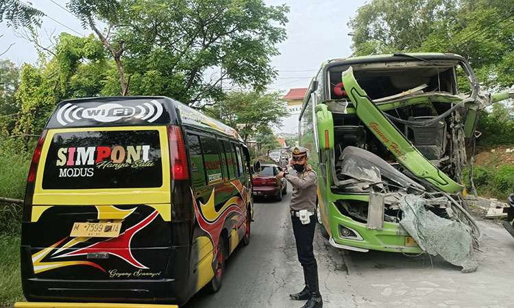 Petugas kepolisian saat mengatur lalu lintas usai kecelakaan yang melibatkan Bus dan Fuso di Jalan Raya Branta Tinggi, Pamekasan.