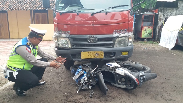 Petugas saat memeriksa kondisi sepeda motor korban yang masih terjepit di bawah truk.