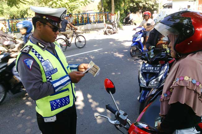 Petugas saat memeriksa kelengkapan kendaraan salah satu pengendara motor. foto: tri susanto/ BANGSAONLINE